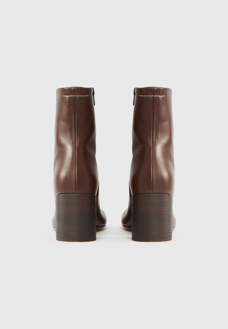 Brown leather ankle boots with a smooth finish, a block heel, and a side zipper. Stitching detail along the upper edge.