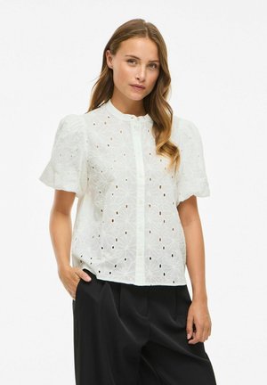 Vit kortärmad blus med intrikata blommönster och utklippta detaljer, med knäppning fram och en avslappnad passform.