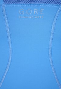 Ljusblå löpartröja i elastiskt material, med mjuk textur, platta sömmar och logotypen "GORE RUNNING WEAR" i silver.