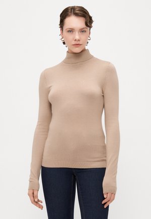 Beige turtleneck sweater with long sleeves, ribbed hem, and a smooth texture. Worn with dark blue jeans, featuring fitted design.