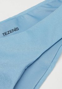Tejido azul claro con un acabado brillante; presenta un patrón acanalado y una etiqueta negra "TEZENIS" en el borde superior. Textura suave y lisa.