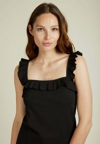 Haut noir à côtes avec décolleté carré et bretelles volantées, avec une silhouette ajustée et une texture lisse.