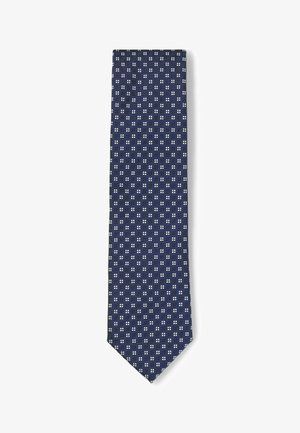 Cravate bleu marine avec un motif géométrique composé de petits carrés blancs, fabriquée en tissu texturé, de forme étroite et avec une pointe.