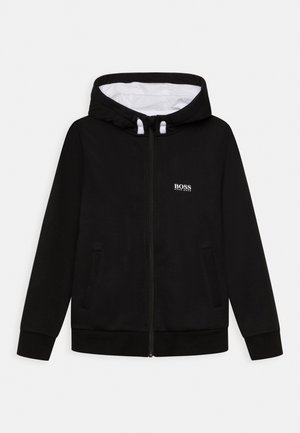 Felpa nera con zip realizzata in un tessuto morbido, caratterizzata da una fodera interna bianca, tasche laterali e un piccolo logo sul petto.