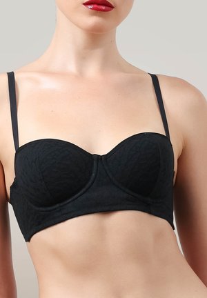 Brassière en dentelle noire présentant un style balconnet structuré avec de fines bretelles, un tissu texturé et une finition lisse.
