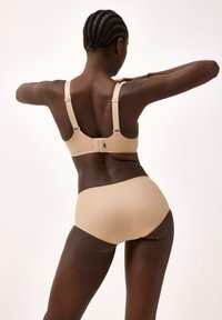 Beige beha en bijpassende high-waisted onderbroek van soepel materiaal, met verstelbare bandjes en een eenvoudig ontwerp met subtiele details.