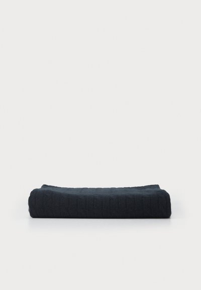 Folded dark blue knitted blanket with a textured cable pattern. Rectangular shape, showing depth and softness with a smooth finish.