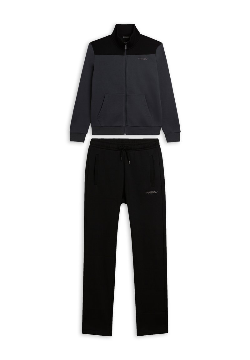 Chándal negro y gris con chaqueta con cremallera, cuello alto y dos bolsillos delanteros, acompañado de pantalones ajustados. Textura suave.