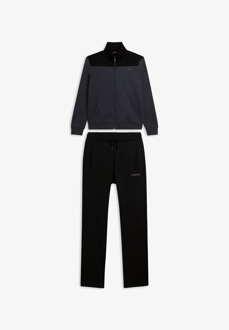 Chándal negro y gris con chaqueta con cremallera, cuello alto y dos bolsillos delanteros, acompañado de pantalones ajustados. Textura suave.