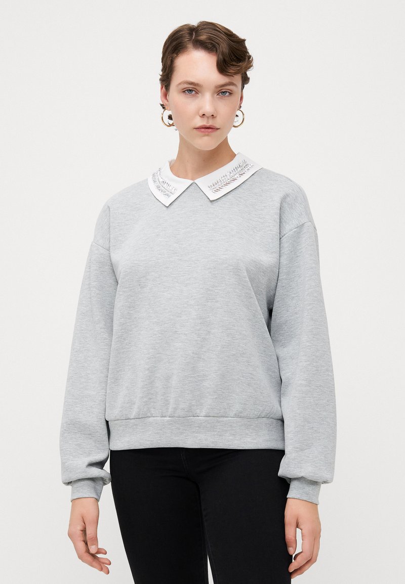 Grauer Sweatshirt mit einem weißen, gestickten Kragen sowie gerippten Bündchen und Saum, mit einem lässigen Schnitt und weicher Textur.