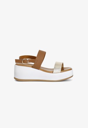 Platform sandals with a brown leather ankle strap, a metallic silver toe band, and a white wedge sole with a textured brown footbed.