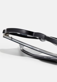 Ochelari negri cu un cadru gros, lentile transparente și accente metalice argintii, având o ușoară curbă și un design ușor.