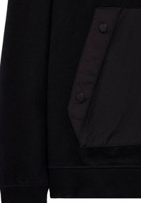Sort sweatshirt med en mat overflade og en struktureret lomme i et kontrasterende blankt materiale, accentueret med sorte knapper.
