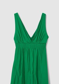 Grünes ärmelloses Kleid mit tiefem V-Ausschnitt, gerafftem elastischem Taillenbund und weichem, fließendem Stoffdesign.