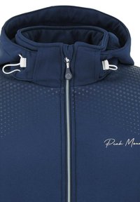 Veste bleu marine avec col montant, fermeture éclair à l'avant et cordon de serrage. Présente un motif texturé à pois et le logo "Peak Mountain" en blanc.