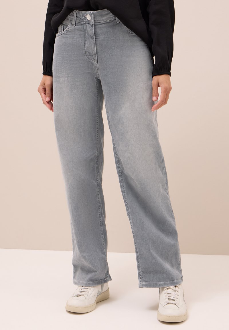 Jeans in denim grigio chiaro con vestibilità dritta, vita media, sfumature delicate e tasche laterali, abbinati a sneakers bianche.