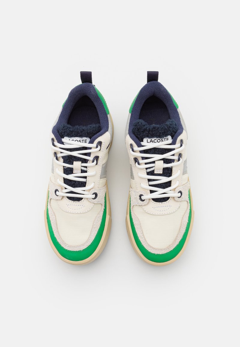 Baskets en cuir crème et textile bleu marine, avec des accents verts, des lacets blancs et une semelle texturée. Étiquetées "Lacoste."