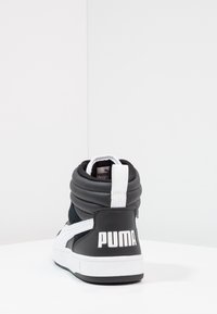 Černé vysoké tenisky s polstrovaným límcem, bílými akcenty, gumovou podrážkou a výrazným logem "PUMA" na patě. Semišové a syntetické materiály.