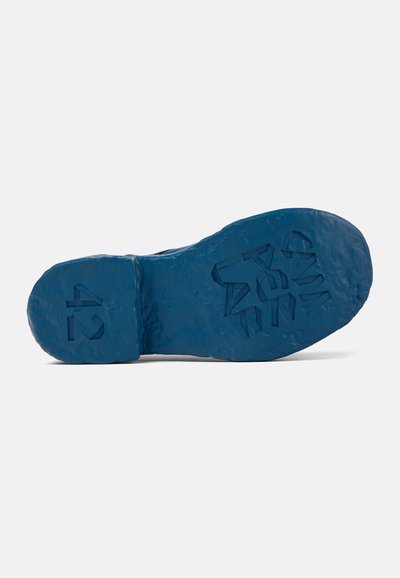 Blue rubber shoe sole featuring textured grip patterns, with size "42" and geometric designs embossed on the surface.