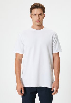Witte katoenen T-shirt met een ronde hals, korte mouwen en een relaxte pasvorm. Geen zichtbare patronen of accenten. Eenvoudig ontwerp.