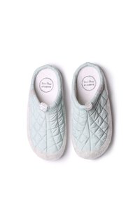 Pantofole trapuntate azzurro chiaro con suola grigia morbida, rivestimento interno bianco e un bottone decorativo all'apertura per una facile vestibilità.
