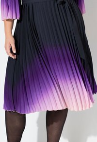 Falda plisada ombre púrpura, que transiciona de púrpura oscuro a rosa claro, con una cinturilla y un tejido suave y texturizado.