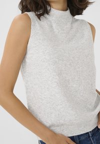 Maglione grigio senza maniche con colletto alla zuava, caratterizzato da una texture morbida e un motivo sottile, infilato in un paio di jeans blu. Nessun hardware o dettaglio visibile.