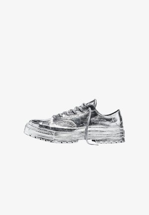 Baskets basses métalliques argentées avec semelle épaisse et lacets attachés, vues de profil sur fond blanc.