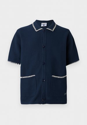 Tengerészkék rövid ujjú gombos ing fehér varrással a galléron, az ujjakon és az első zsebeknél, a zsebnél kis hímzett részlettel.