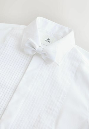 Weißes Hemd mit gefältelter Vorderseite, umgeschlagenem Kragen und einer passenden weißen Fliege mit strukturiertem Punktmuster. Markenetikett sichtbar.