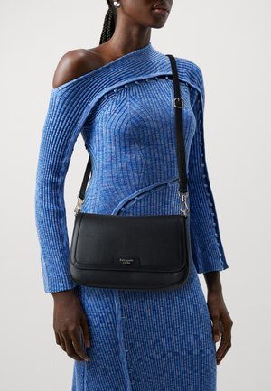 Black leather shoulder bag with a textured finish, featuring silver-tone hardware and a flap closure. Worn crossbody with adjustable strap.