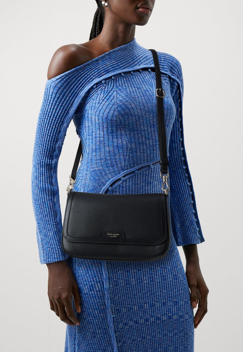 Black leather shoulder bag with a textured finish, featuring silver-tone hardware and a flap closure. Worn crossbody with adjustable strap.