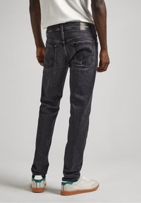 Mörkgrå denimjeans med slim fit, fem fickor och en läderlapp på baklinningen. Matchas med vita sneakers med turkosa detaljer.