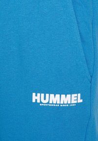 Blauwe stoffen sweatshirt met een gladde textuur, voorzien van een opvallend wit "HUMMEL" logo en de tekst "SPORTSWEAR SINCE 1923".