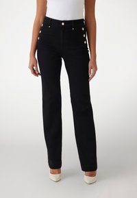 Jeans negros de talle alto con corte recto, que presentan cinco botones decorativos dorados en el costado y una textura vaquera clásica.