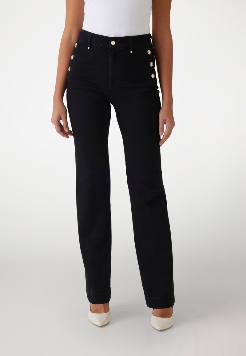 Jeans negros de talle alto con corte recto, que presentan cinco botones decorativos dorados en el costado y una textura vaquera clásica.