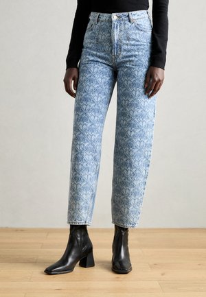 Jeans in denim blu chiaro con un motivo geometrico, a vita alta e dal taglio dritto, abbinati a stivaletti neri. 