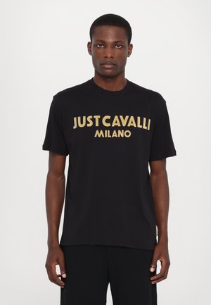 Czarny bawełniany t-shirt z dużym złotym napisem "JUST CAVALLI MILANO" na przodzie. Krótkie rękawy i okrągły dekolt.