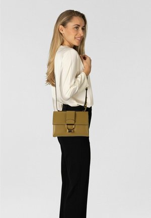 Leicht olivgrüne Leder-Umhängetasche mit magnetischer Klappe und runden Metallakzenten. Rechteckige Form, glatte Oberfläche und verstellbarer Riemen.