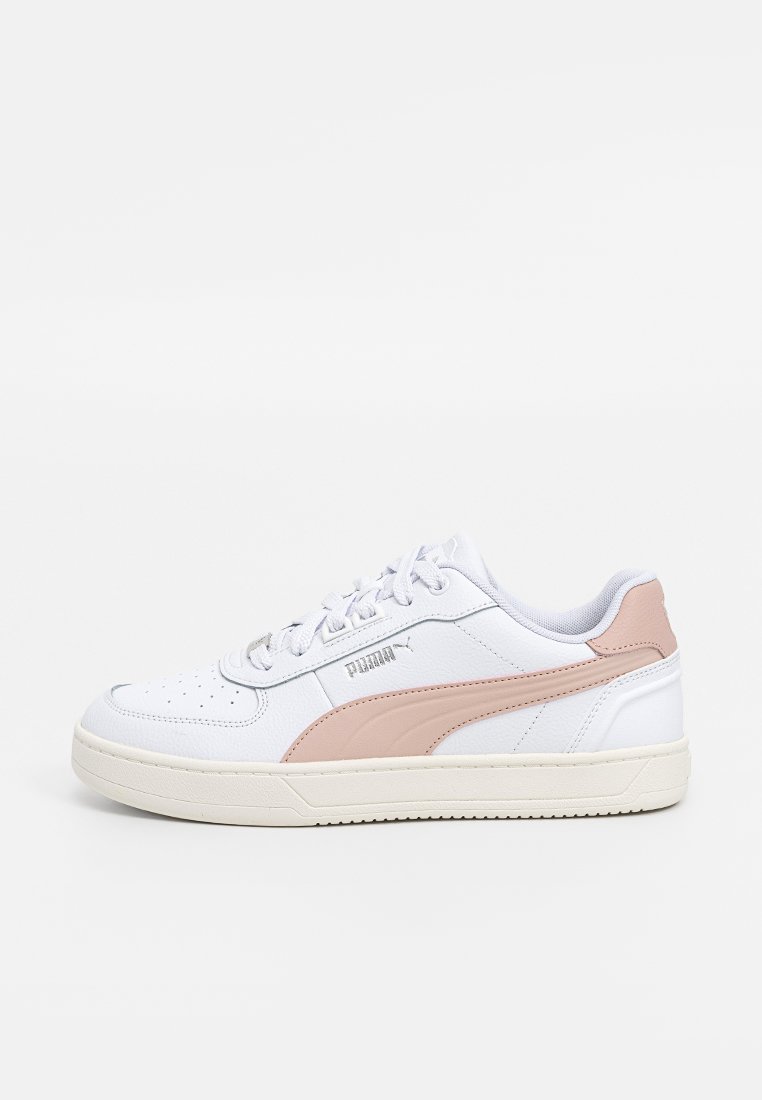 Baskets de sport blanches avec une bande latérale rose, en cuir, tige texturée, semelle en caoutchouc plate et système de laçage.