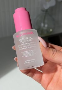 Olio Anti-Crespo per Capelli Slick in una bottiglia trasparente con tappo a pompa rosa; etichettata con dettagli del prodotto in testo bianco, 30 ml, di proprietà australiana.
