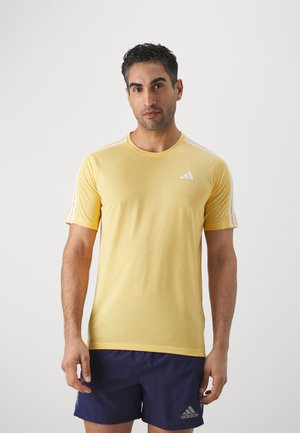 Camiseta atlética amarilla de manga corta, con cuello redondo y logotipo de Adidas en blanco. Presenta tres stripes blancas en los hombros. Tela suave, ajuste regular.