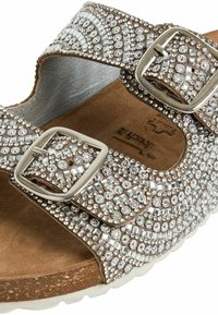 Sandalo marrone con decorazioni in strass, doppie cinghie regolabili, accenti metallici e suola testurizzata simile al sughero.