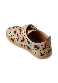 Beżowy płócienny but z kolorowymi nadrukami zwierząt, elastycznym paskiem i brązową gumową podeszwą. Zaokrąglony kształt i miękka, teksturowana podszewka.
