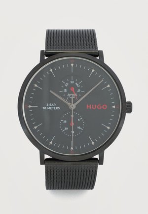 Must käekell võrguvööga, analoogkuvar ajal, päeva sihverplaadi ja alamsekundi sihverplaadiga, bränditud nimega "HUGO", veekindel kuni 30 meetrit.