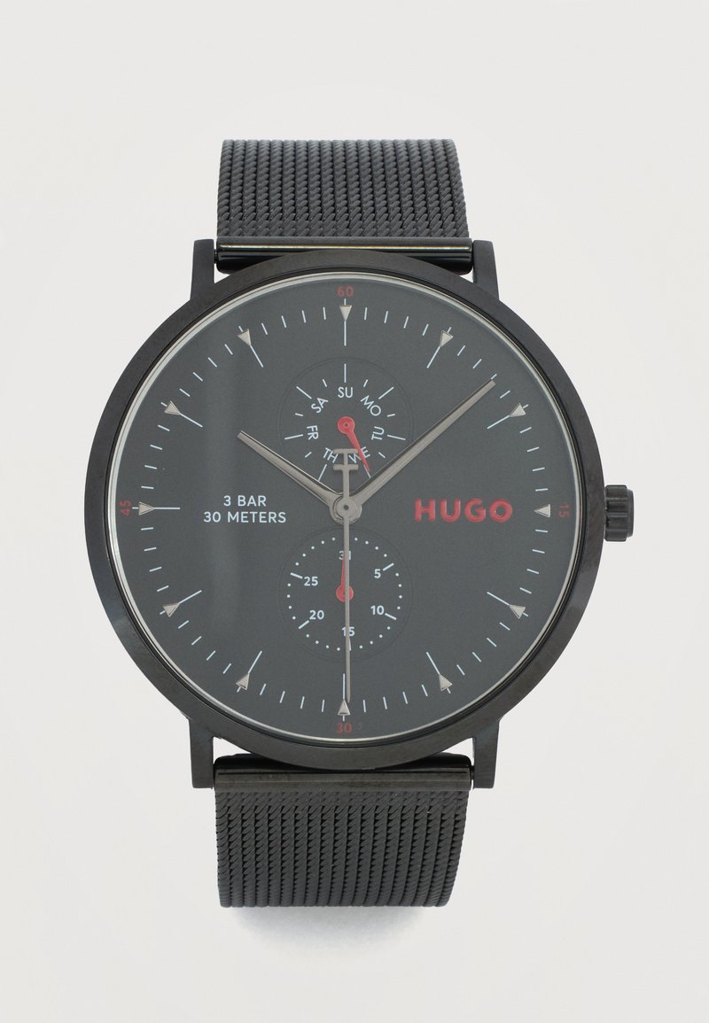 Μαύρο ρολόι χειρός με μπρασελέ από πλέγμα, αναλογική οθόνη που δείχνει την ώρα, καντράν ημέρας και υποκαντράν δευτερολέπτων, με την επωνυμία "HUGO", ανθεκτικό στο νερό έως 30 μέτρα.