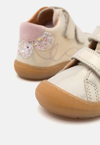 Silberne Kunstleder-Schuhe mit Klettverschluss, Gummisohlen und einem pinken Wildleder-Helm; mit einem glitzernden Blumenmuster an der Seite.