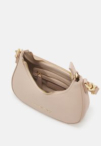 Bolsa de pele bege com uma forma estruturada, fecho dourado e acessórios em metal. O interior possui múltiplos compartimentos para armazenamento.
