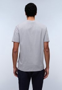 T-shirt en coton gris clair avec des manches courtes, un col rond et un ourlet droit ; présente une étiquette sur le côté inférieur.