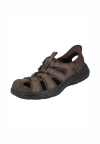 Zapato de agua sintético marrón con diseño recortado y correas ajustables, que presenta una superficie texturizada y suela de goma negra resistente.